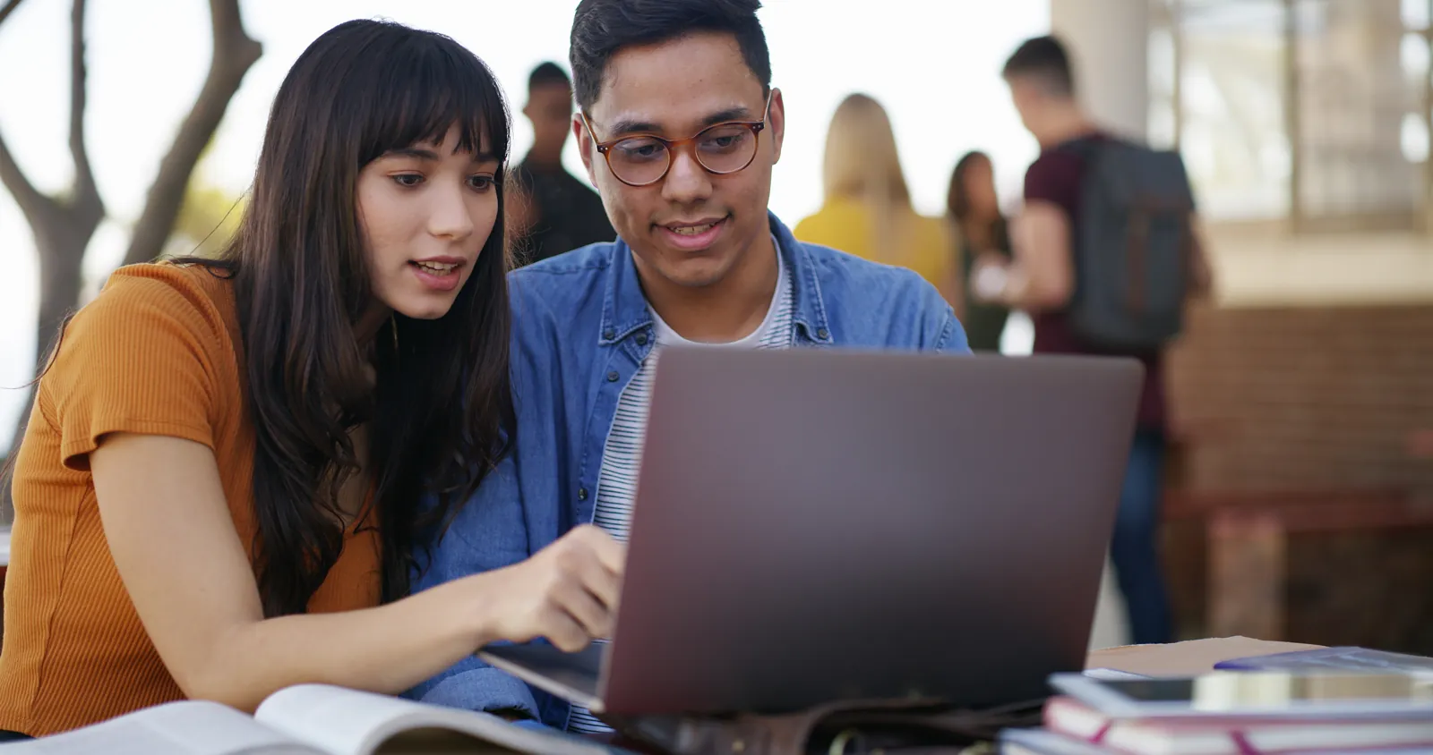 Dos postulantes de una academia preuniversitaria virtual revisando juntos un simulacro de admisión en su laptop
