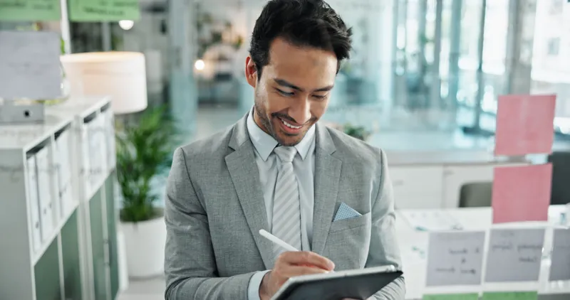Empresario firmando con lápiz digital en una tablet en su oficina, una forma de firma electrónica distinta del certificado digital de un curso