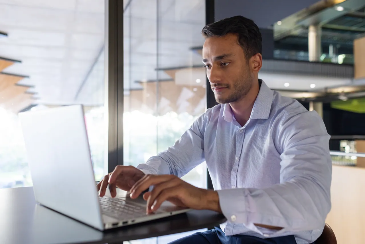 Empresario configurando su correo corporativo en el celular junto a su laptop en la oficina
