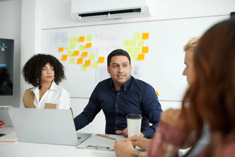 Gerente de una empresa conversando con su equipo en una reunión para decidir si hacer un software a medida o usar una herramienta existente