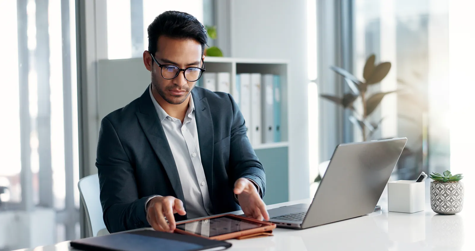 Empresario revisando en su laptop y su tablet el presupuesto de tecnología de su pyme para el próximo año