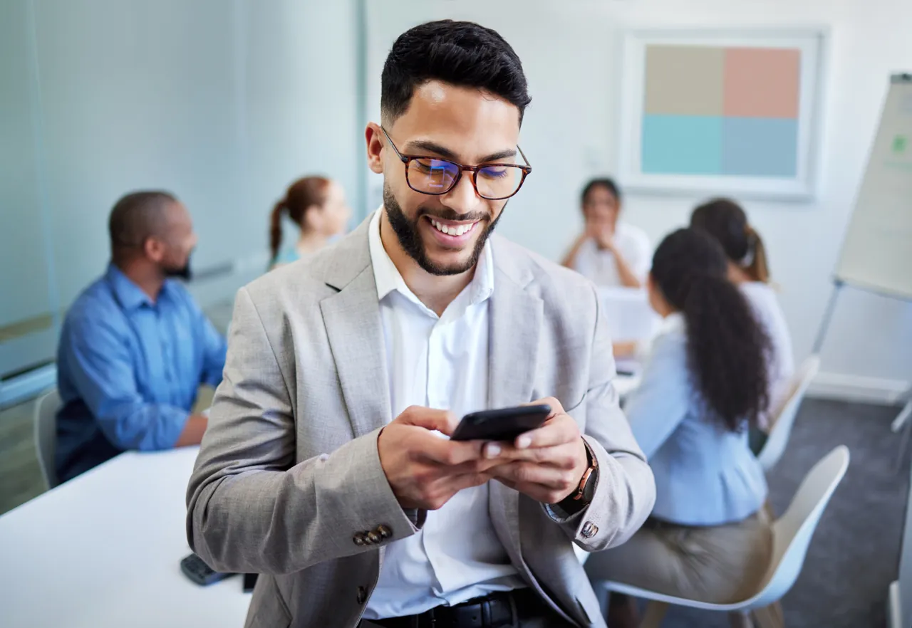 Profesional revisando en su celular una actividad interactiva del curso en la oficina, entre reuniones