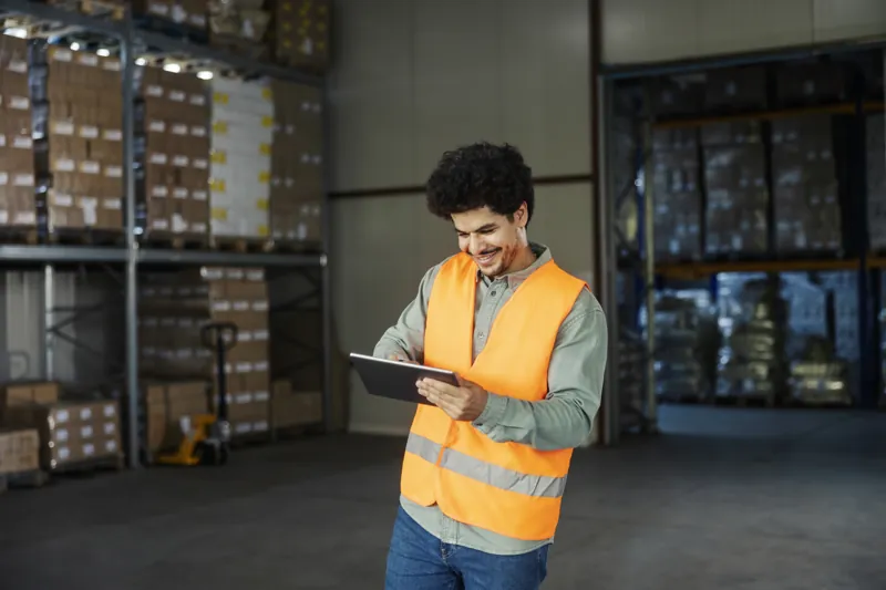 Encargado de almacén revisando en su tablet el stock del sistema de inventario y ventas entre los estantes de mercadería