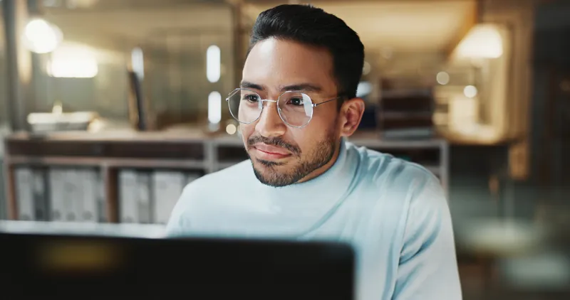 Coordinador académico con lentes revisando en su computadora las novedades de Moodle 2026 para el aula de su instituto