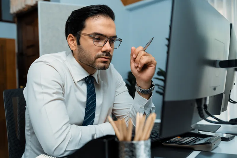 Director de un instituto con lentes y corbata pensando frente a su computadora si elegir Moodle Cloud o un servidor propio
