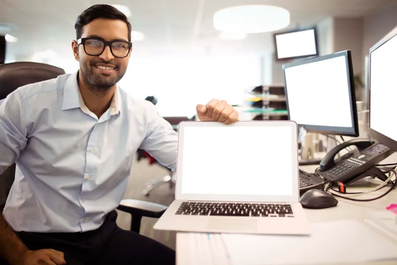 Director de un centro de capacitación sonriendo en su oficina con una laptop abierta, comparando Moodle vs Google Classroom