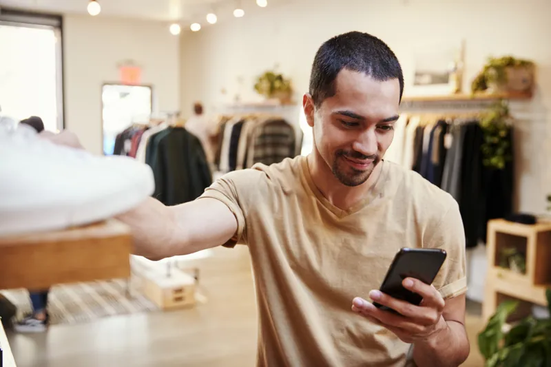 Dueño de una tienda de ropa revisando en su celular un pago con Yape de su tienda virtual