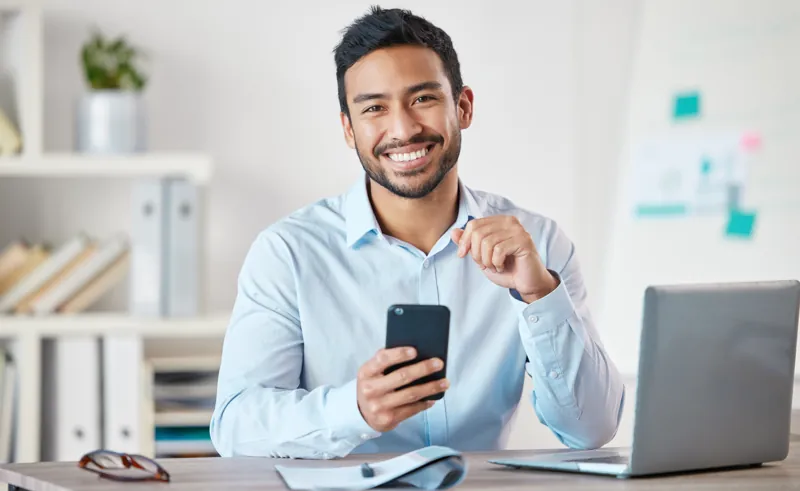 Dueño de un negocio peruano sonriendo mientras responde mensajes de clientes por WhatsApp Business en su celular